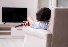 Hidden Muscle Damage From Sleep Apnea Person lying on a sofa holding a TV remote