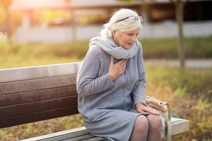 shutterstock_1206866299 Older woman on park bench holding chest