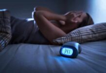 3 A.M. Insomnia Hack Sparks Big Debate Person lying awake in bed beside a glowing digital alarm clock