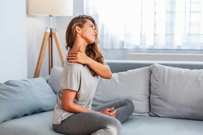 shutterstock_1493802077 Woman sitting on couch holding her neck
