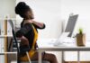 Woman at desk rubbing her neck and lower back