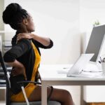 Woman at desk rubbing her neck and lower back