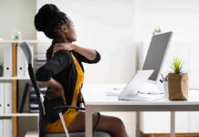 Back Pain Explosion: WHO Sounds Alarm Woman at desk rubbing her neck and lower back