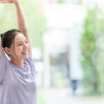 woman stretching with arms raised indoors near window