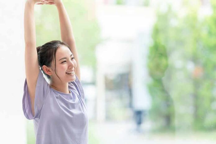woman stretching with arms raised indoors near window