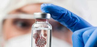 Gloved hand holding a small vial in a lab