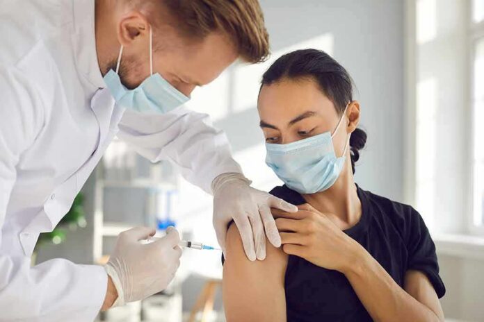 shutterstock_1903346662 Healthcare worker giving a masked patient a vaccine in the upper arm