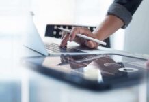 Fitness Dashboards: Breakthrough Or Fitness Trap? Person using laptop with stylus near tablet