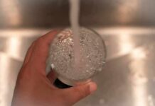Hand holding a glass under a running faucet