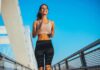 Smiling woman jogging on a bridge under a clear blue sky