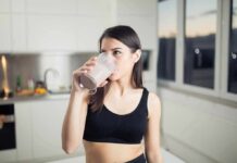Gym Staple Tied To Tumor Fight Woman in sportswear drinking a smoothie in a kitchen