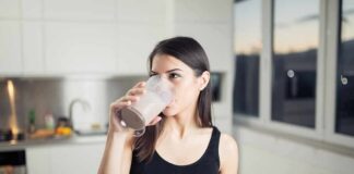 Woman in sportswear drinking a smoothie in a kitchen