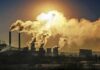 Industrial plant with smokestacks emitting thick smoke at sunset