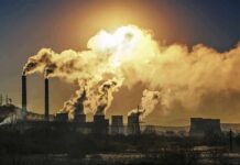 Industrial plant with smokestacks emitting thick smoke at sunset