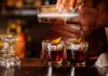 Bartender pouring cocktails into two rocks glasses