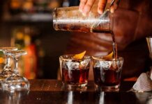 Bartender pouring cocktails into two rocks glasses